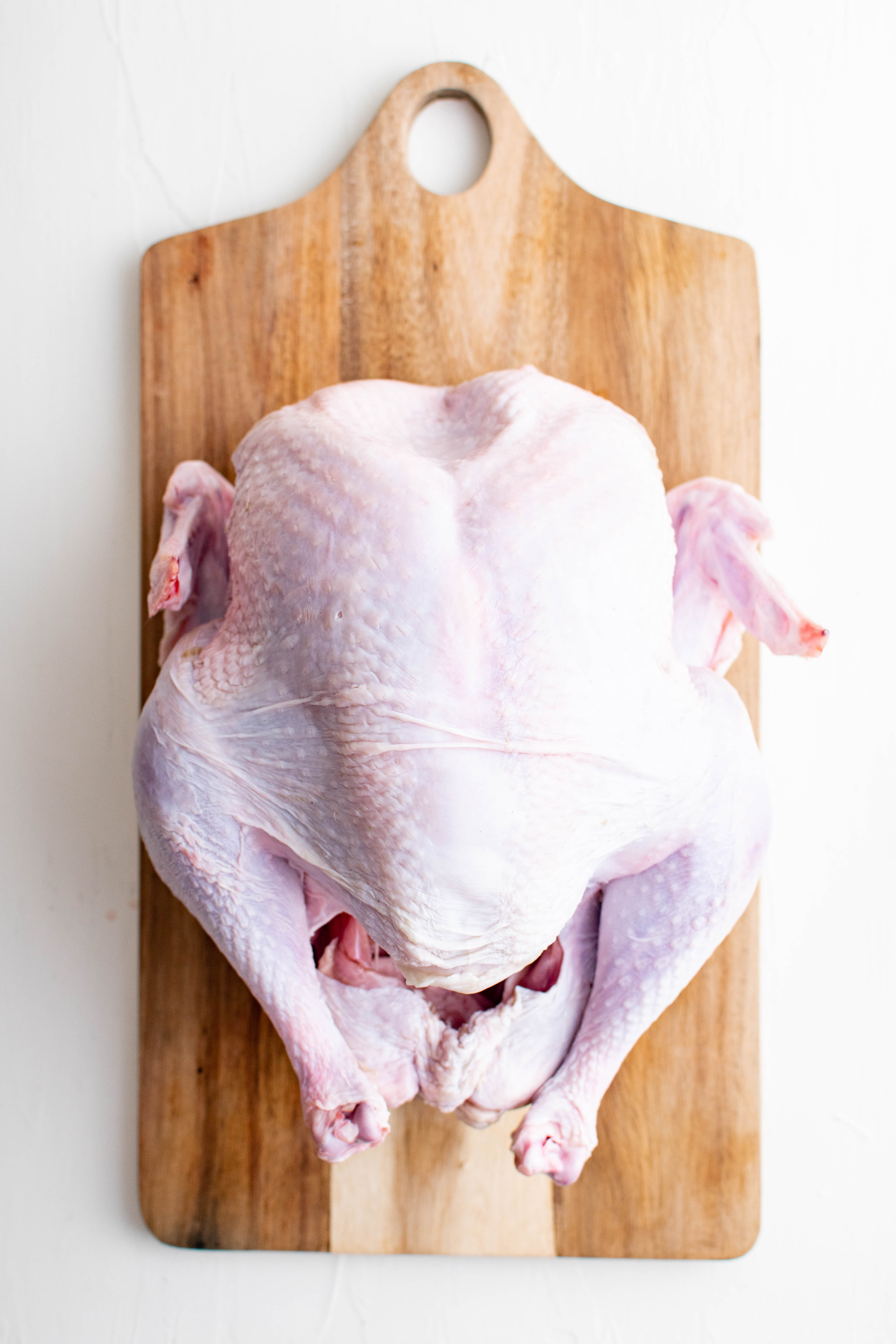 Uncooked whole turkey on a wood cutting board.