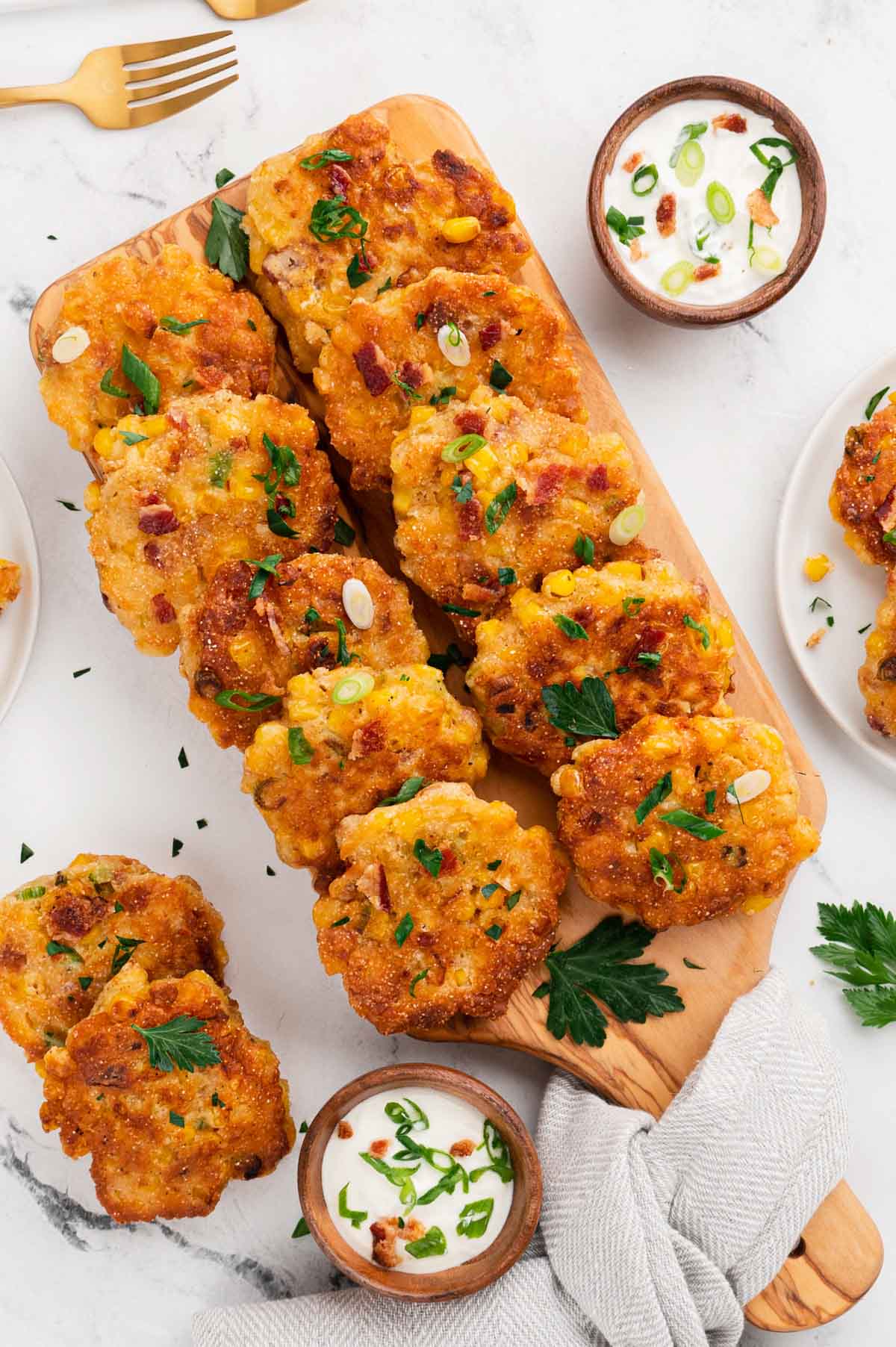 Mini Corn Cakes, fanned out on a wooden cutting board, with dishes of dip, and sliced green onions.