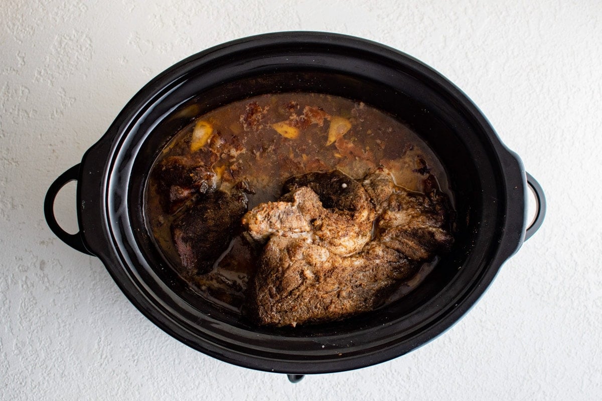 Corked pork roast in a slow cooker with juices.