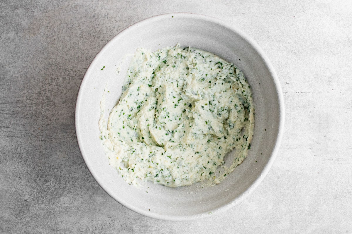 whipped ricotta with fresh herbs stirred in a bowl.