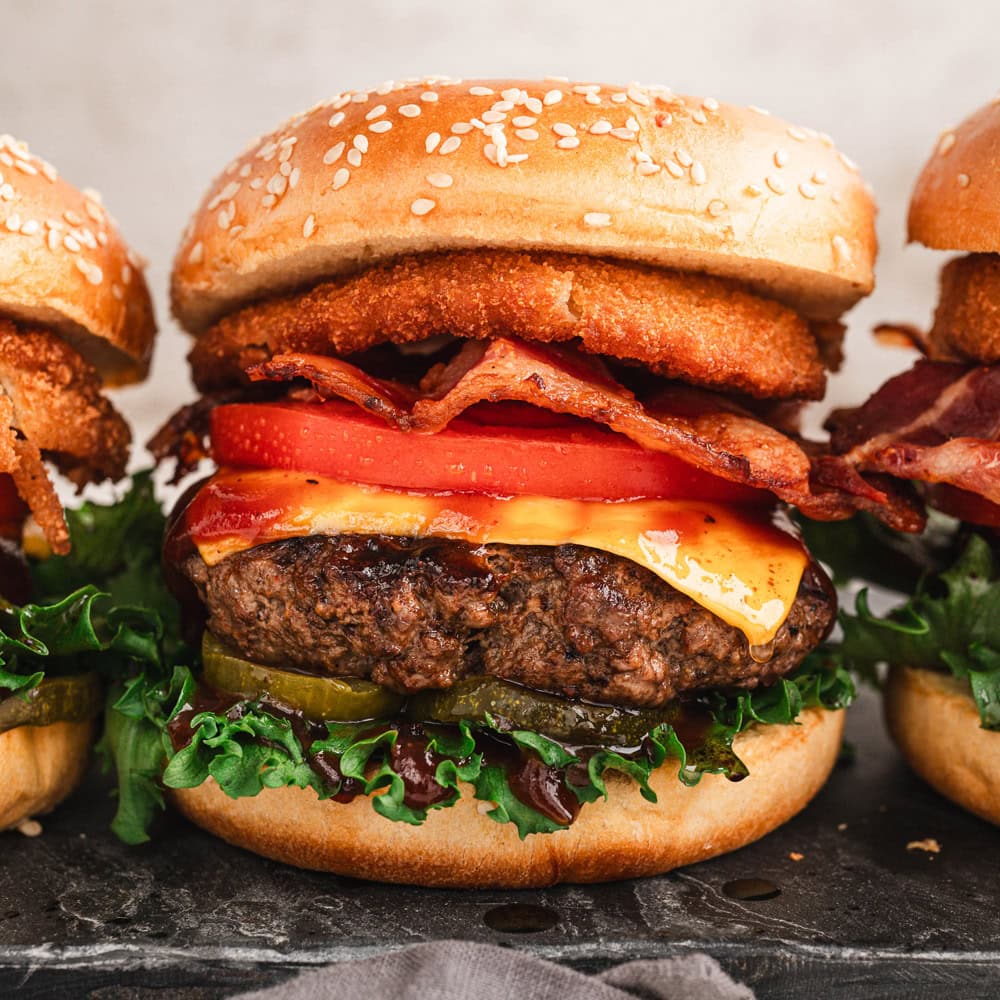 A loaded up bbq bacon cheeseburger with lettuce tomatoes and pickles.