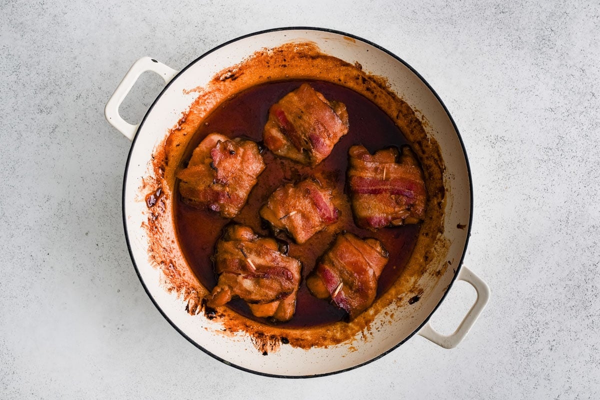 Crispy bacon wrapped chicken thighs in a skillet,
