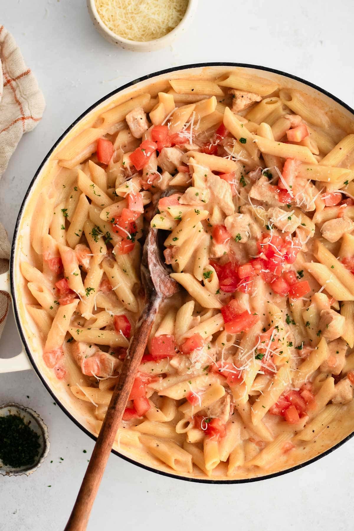 Large skillet with chicken, pasta and fresh diced tomatoes.