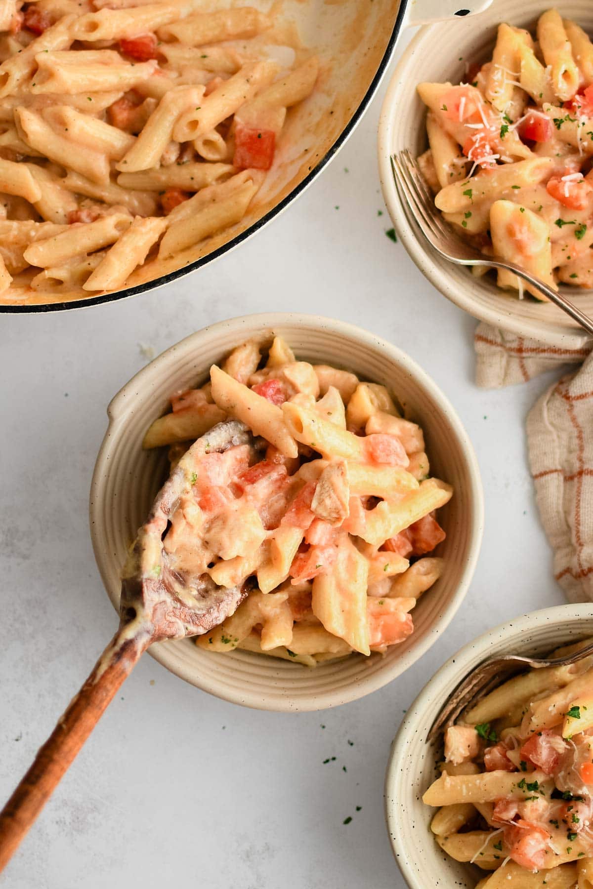 Cajun chicken pasta in bowls and with a wooden spoon.