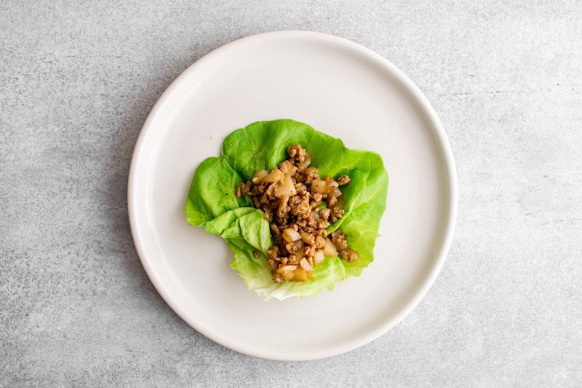 Chicken lettuce wrap on a white plate.