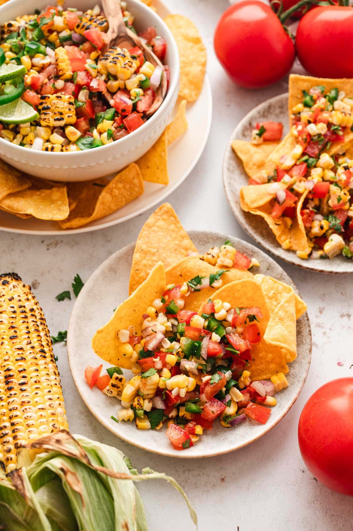 Corn salsa in a bowl and on small plates with tortilla chips.