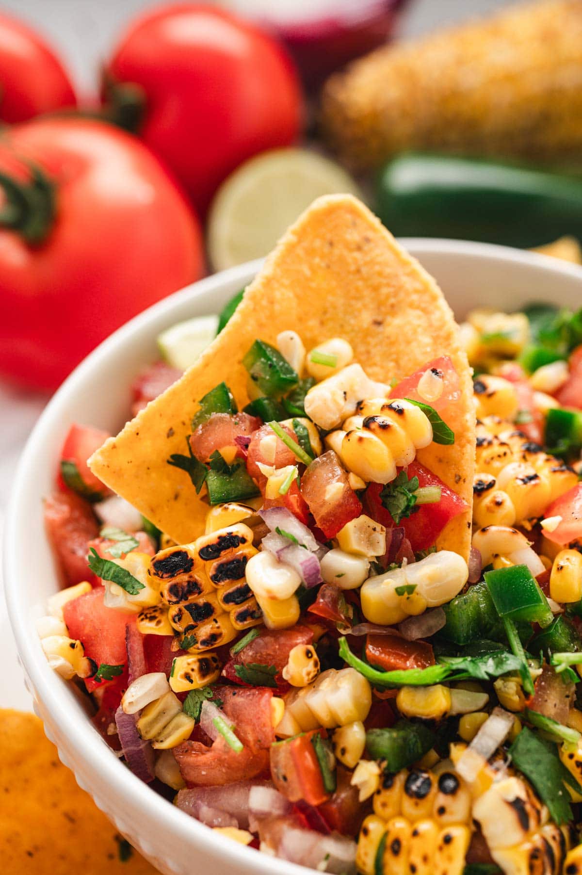 Corn salsa in a white bowl with a tortilla chip.