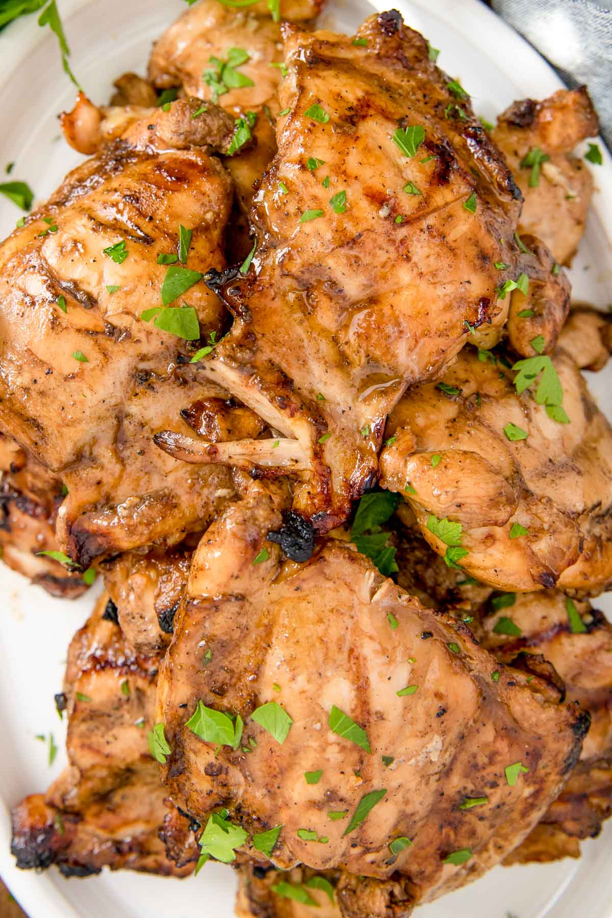 Grilled chicken thighs on a white platter. 