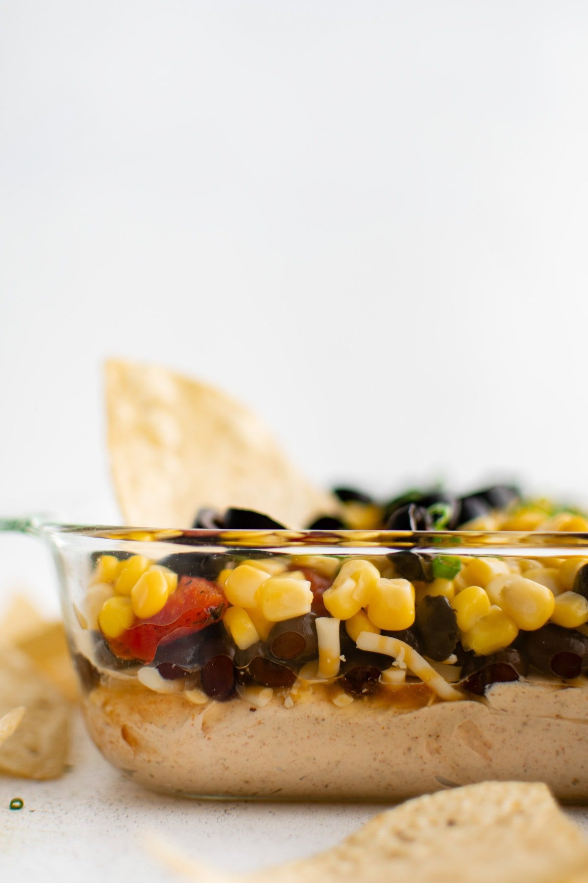 side view of creamy southwest dip with layers of corn, black beans and olives.