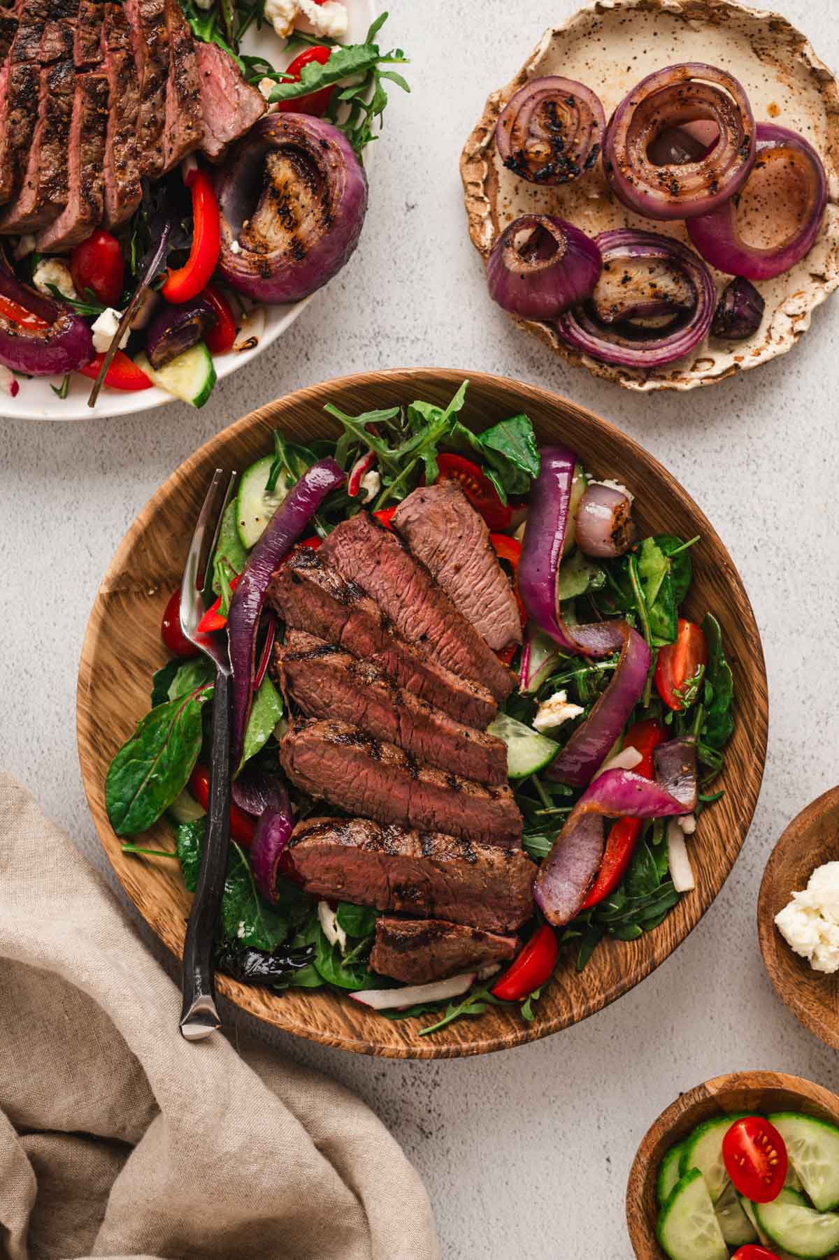Steak salad on a wood plate.