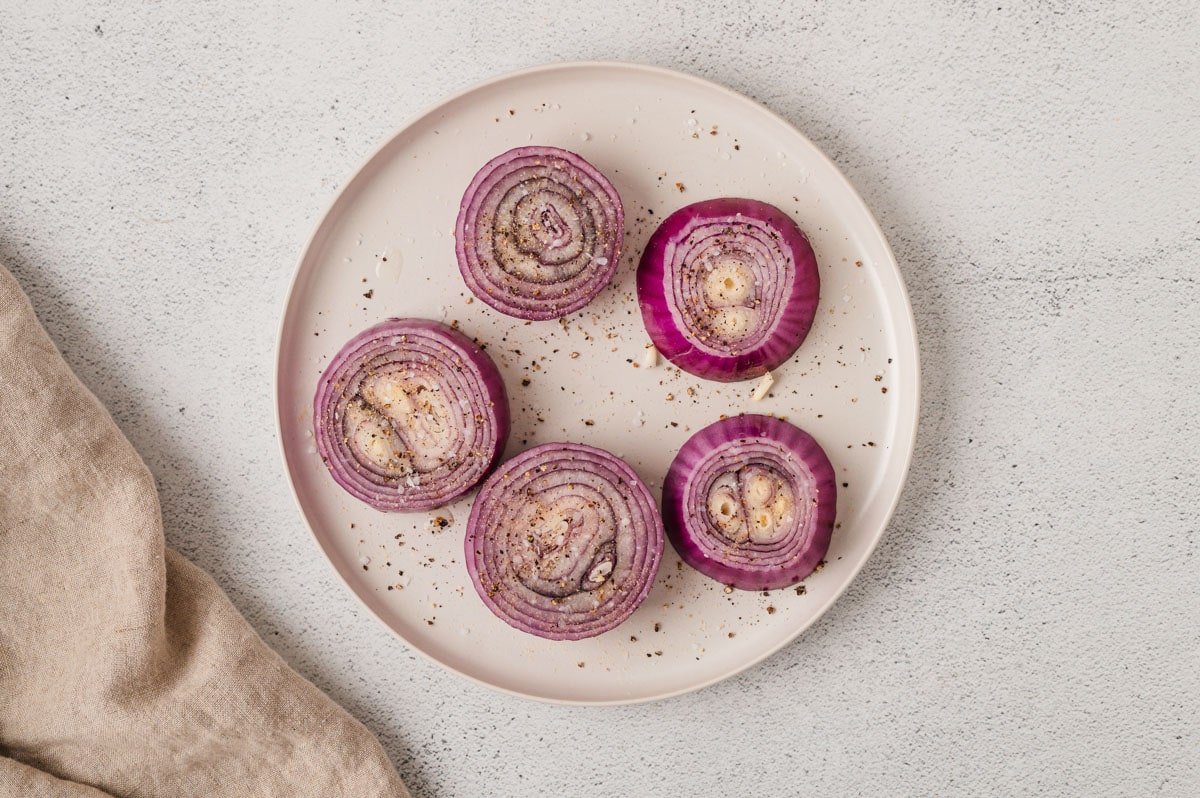 Red onions rounds on a white plate.