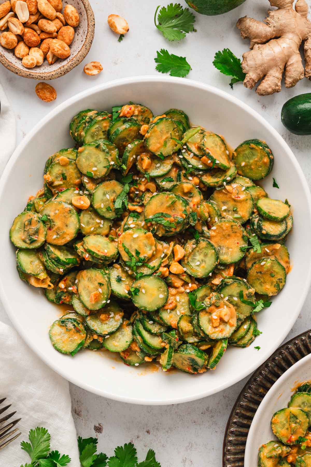 Sliced cucumbers in peanut dressing in a white bowl.