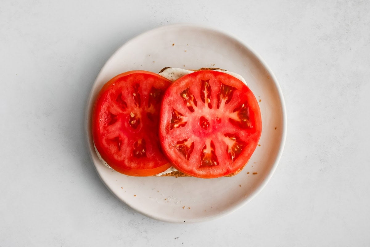 Two slices of tomato on a slice of bread on a plate.
