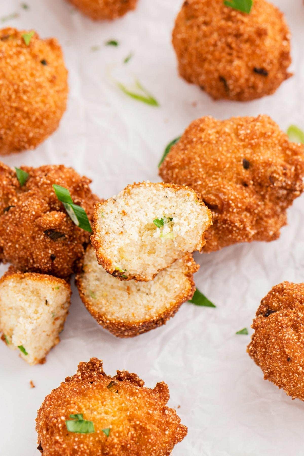 Hush puppies with one sliced in half to reveal the fluffy insides.