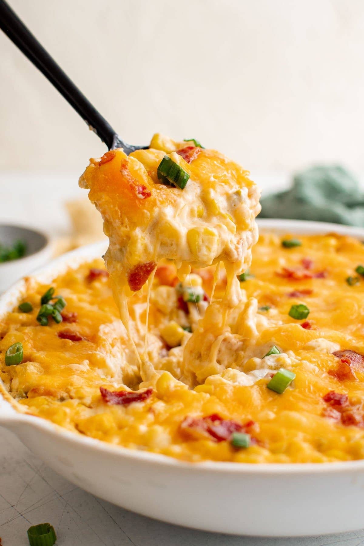 spooning a portion of corn dip in a white dish