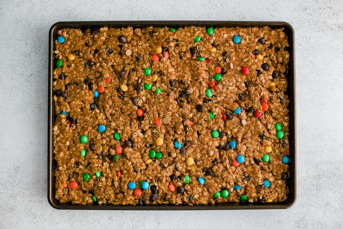 monster cookie bar batter spread in a large pan.