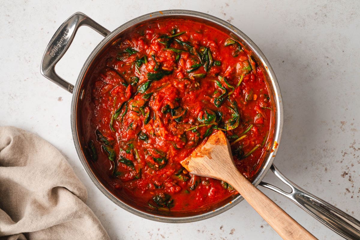 Marinara sauce with spinach in a saute pan.