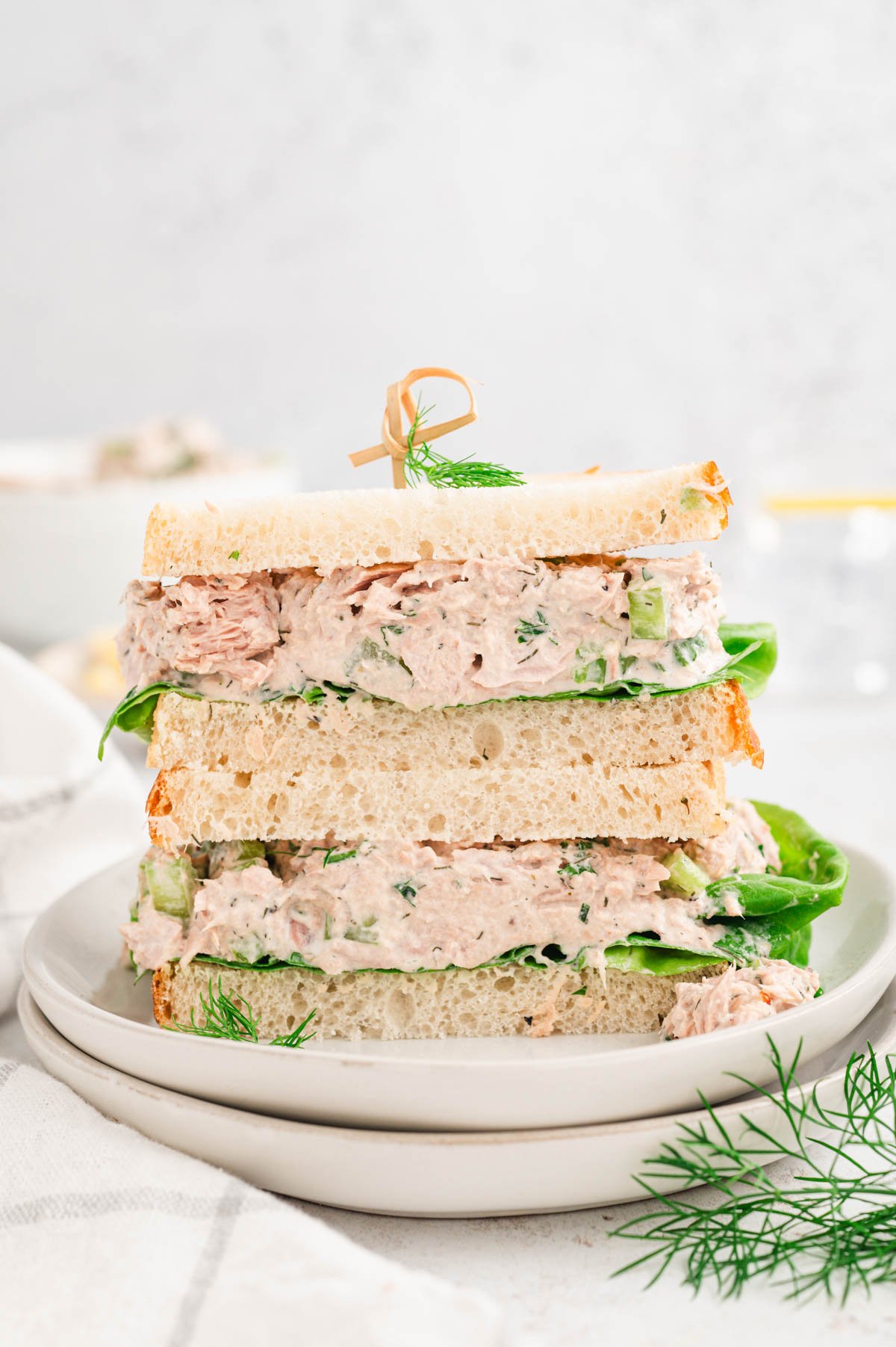 Tuna salad sandwich, with the two halves stacked on a white plate.