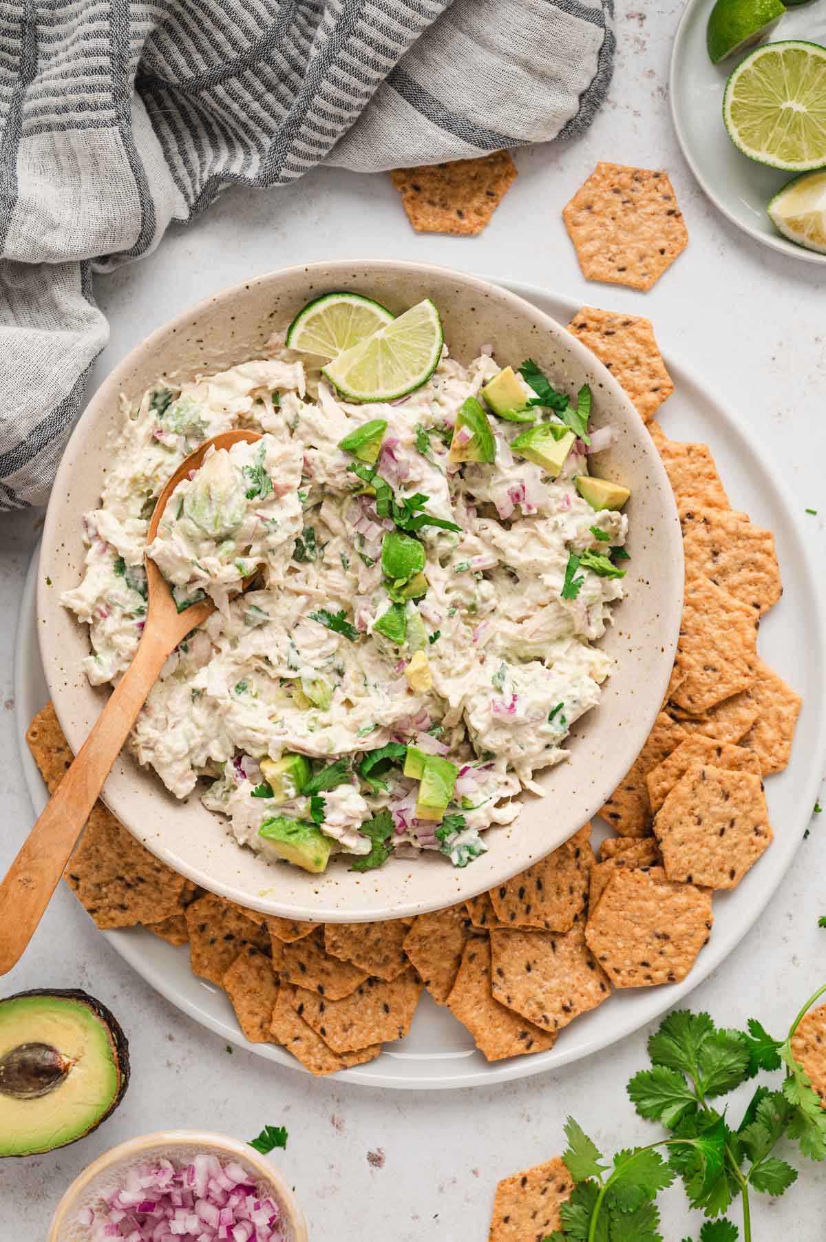 Bowl of avocado chicken salad in a white bowl surrounded by crackers.