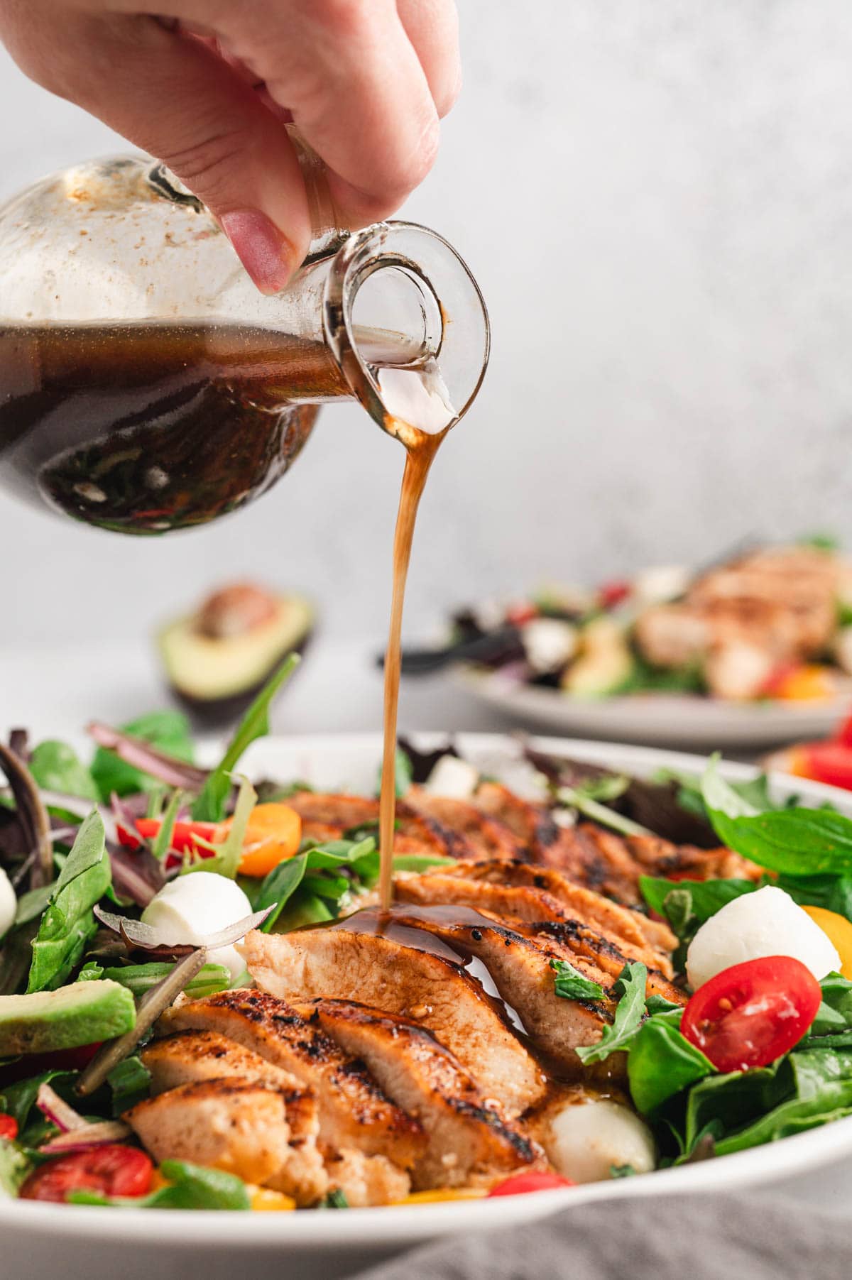 Balsamic dressing drizzled over a chicken caprese salad.