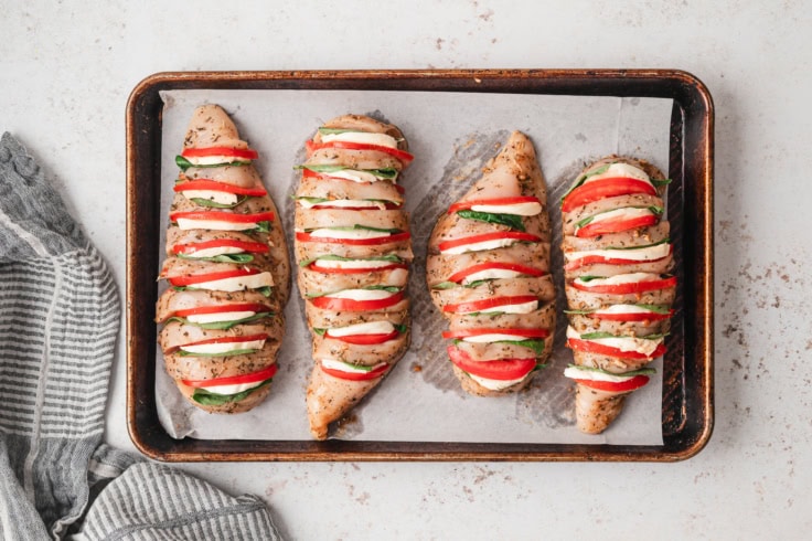 Caprese stuffed chicken breasts on a cookie sheet.