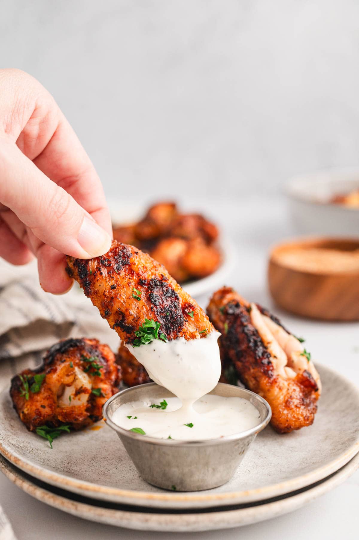 A hand holding a chicken wings dipped in ranch dressing.