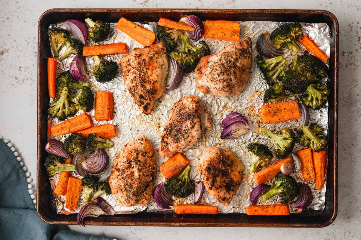 Baked chicken broccoli and carrots on a sheet pan.