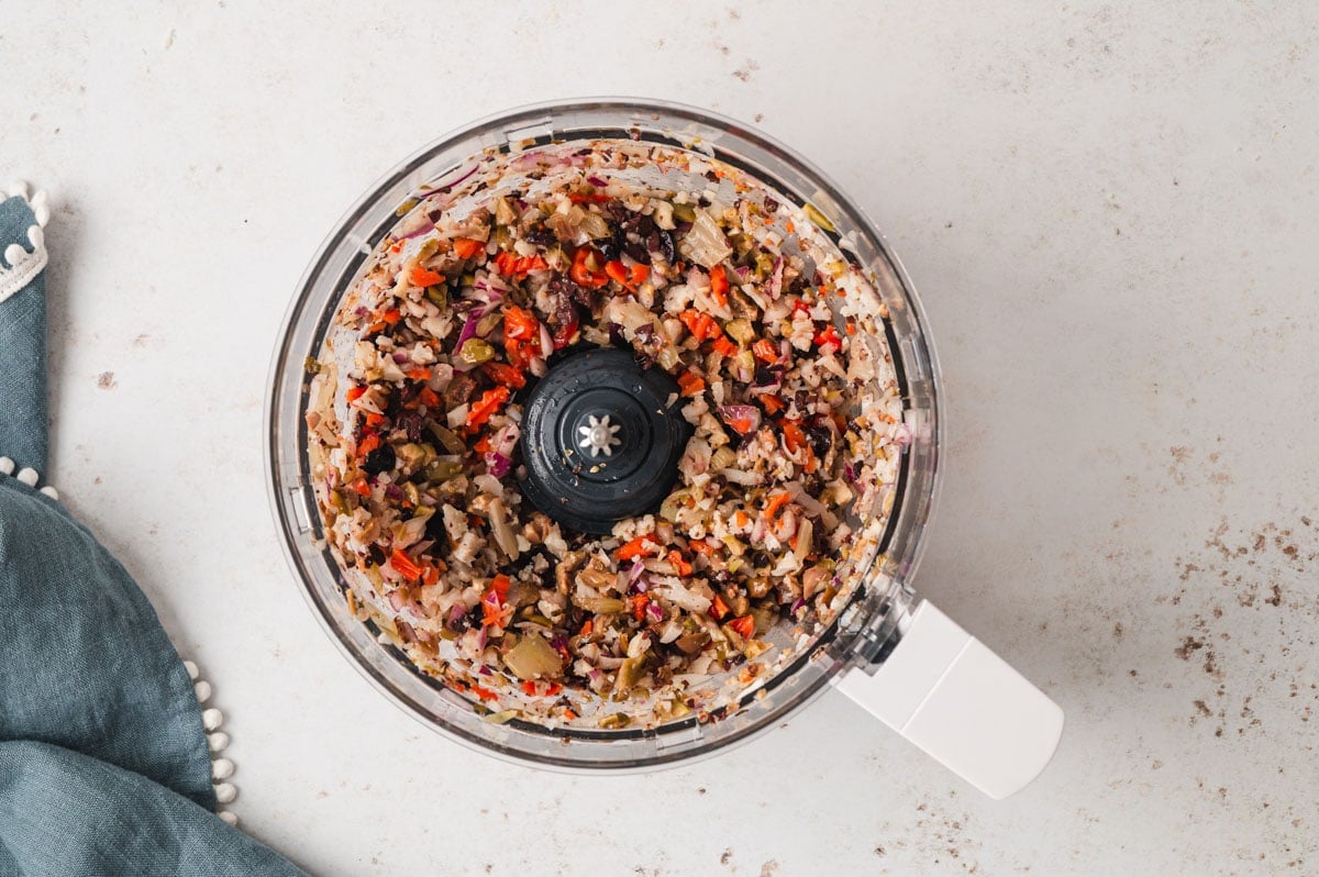 Food processor bowl with minced olives and vegetable.