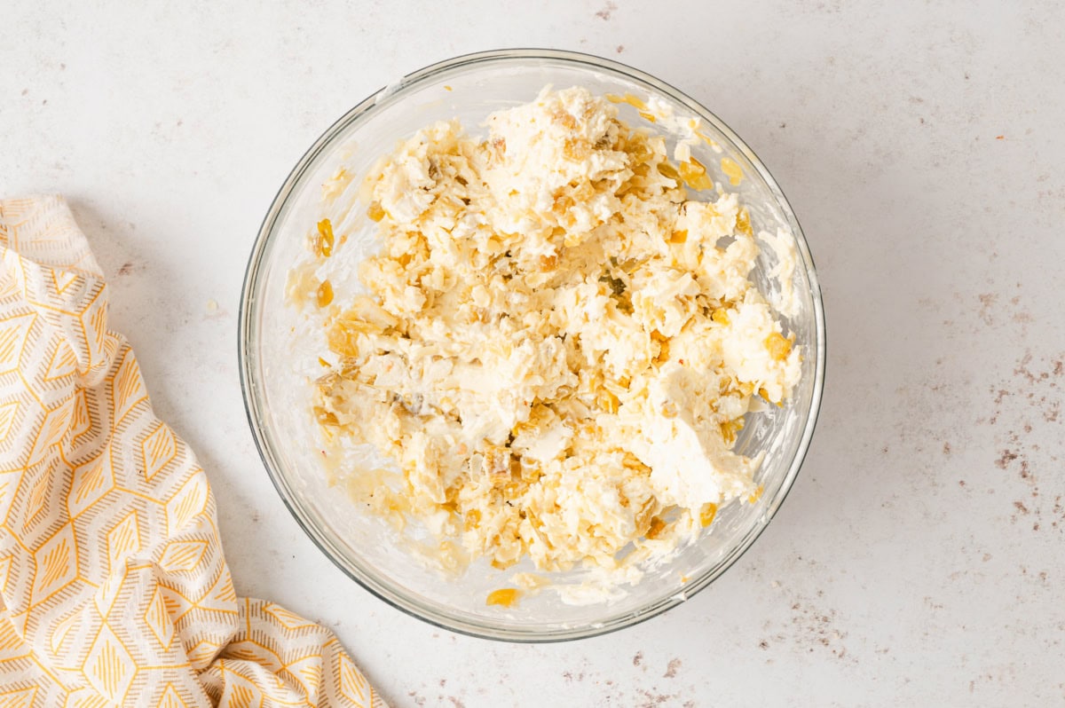 Cream cheese, shredded white cheeses and green chiles mixed together in a bowl.