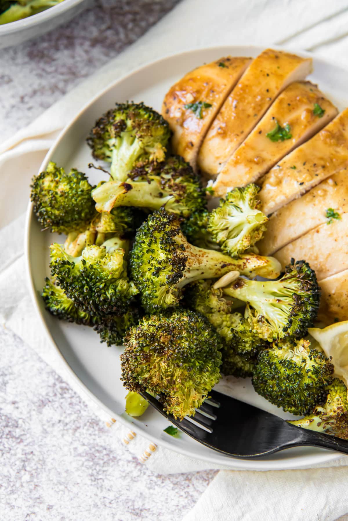 roasted broccoli with a sliced chicken breast on a plate.