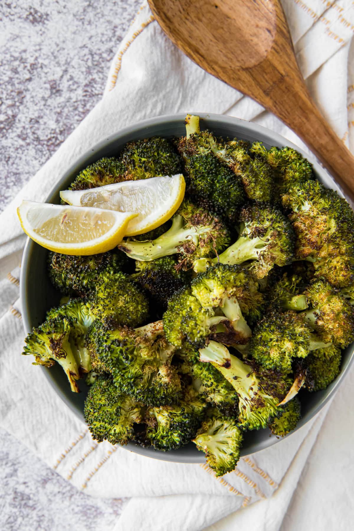 roasted broccoli with a lemon slices in a white bowl