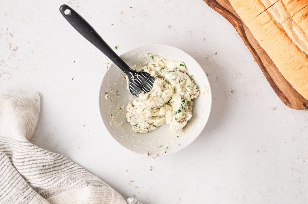 Garlic butter in a white bowl with a pastry brush.