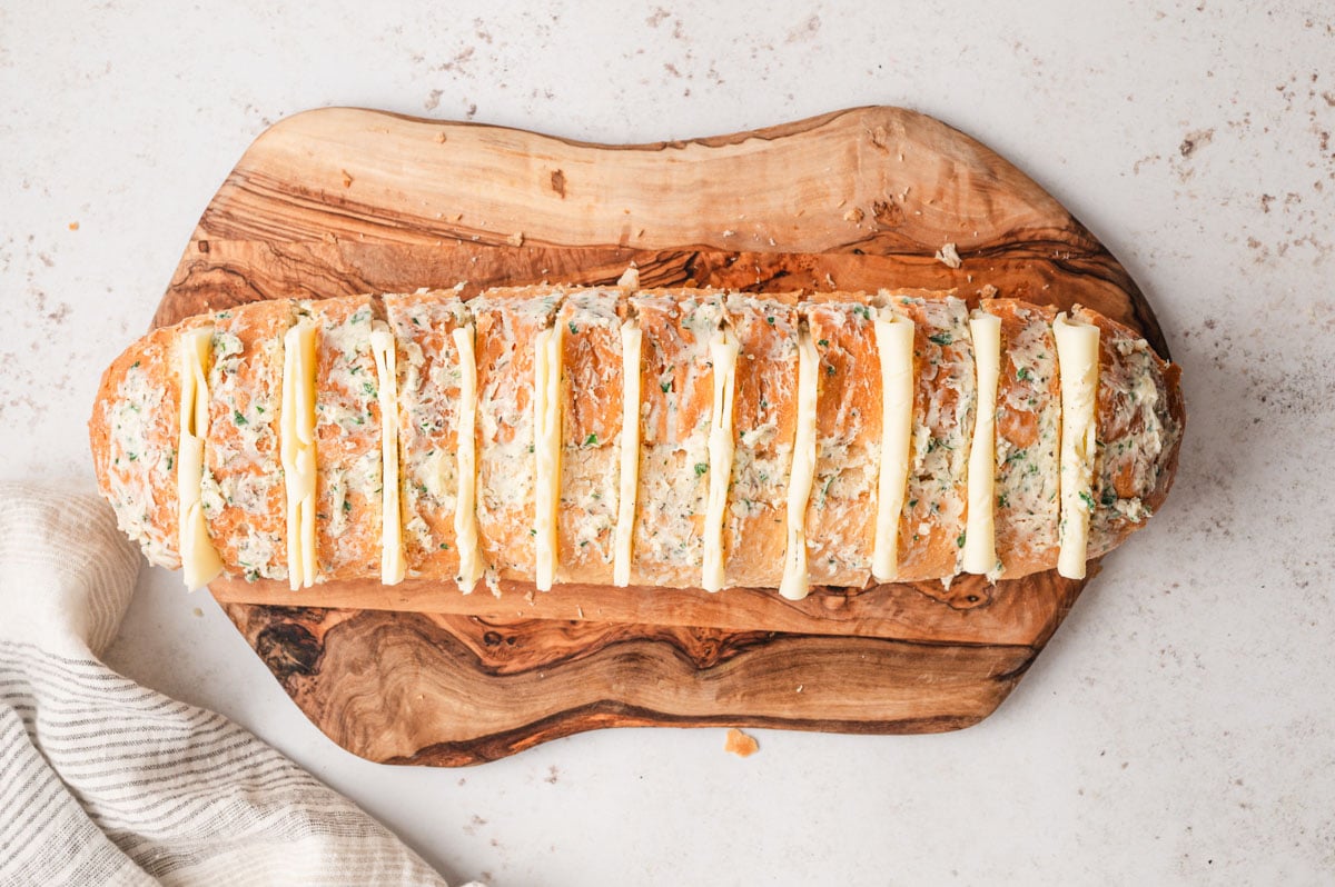 Sliced italian loaf with garlic butter and Mozzarella between the slices.