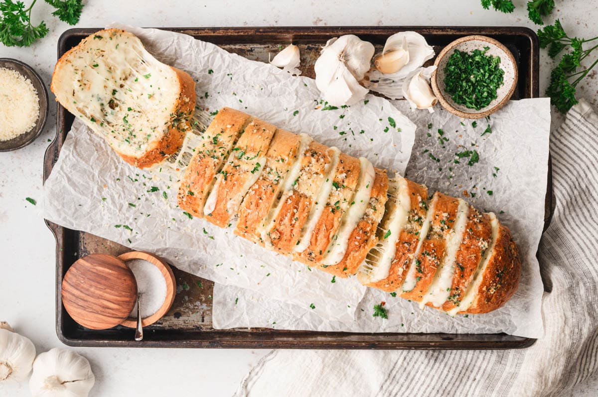 Cheese stuffed garlic bread on a cookie sheet.