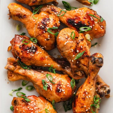 Chicken drumsticks on a white platter.