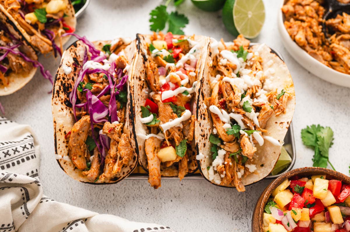 Chipotle chicken tacos with cabbage and pico toppings on taco stands.