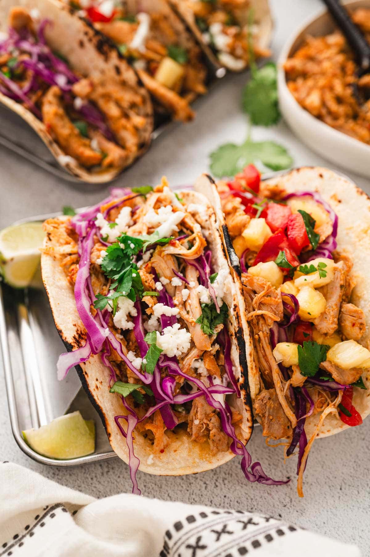 Chipotle chicken tacos with pineapple salsa and cabbage on taco stands.