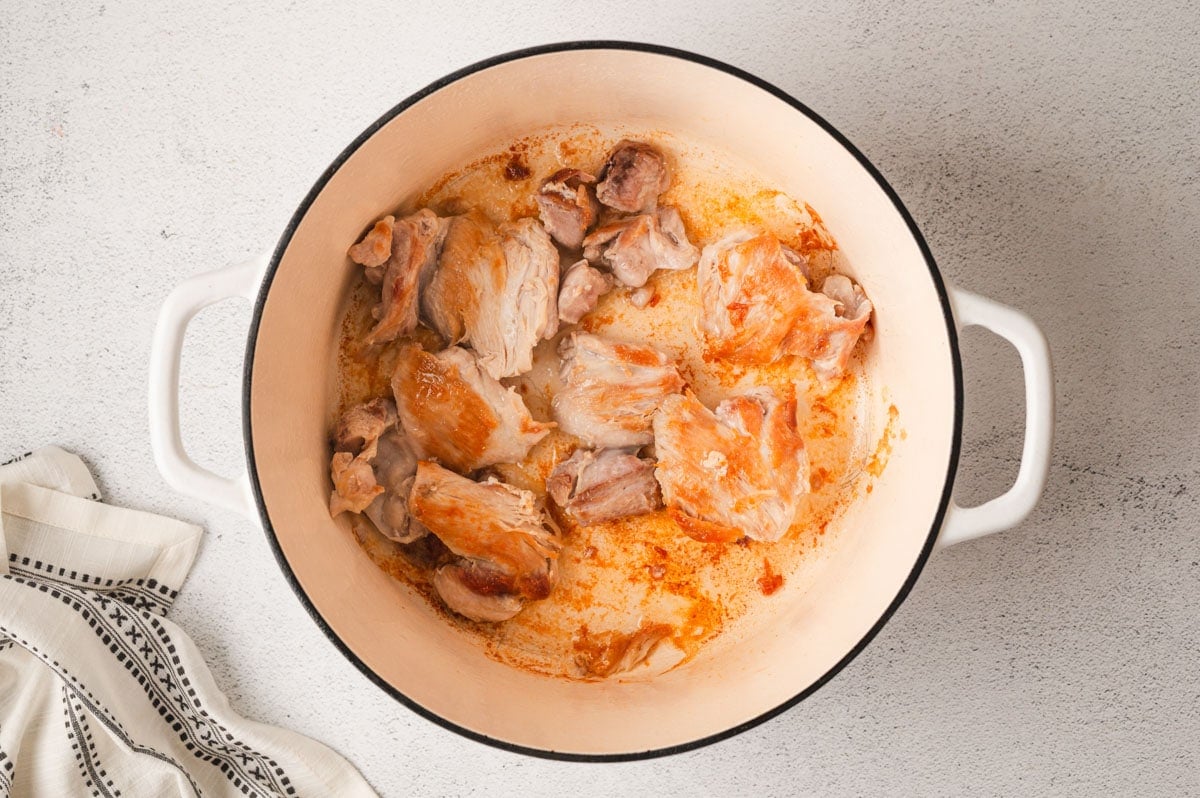 Browned chicken thighs in a large pot.