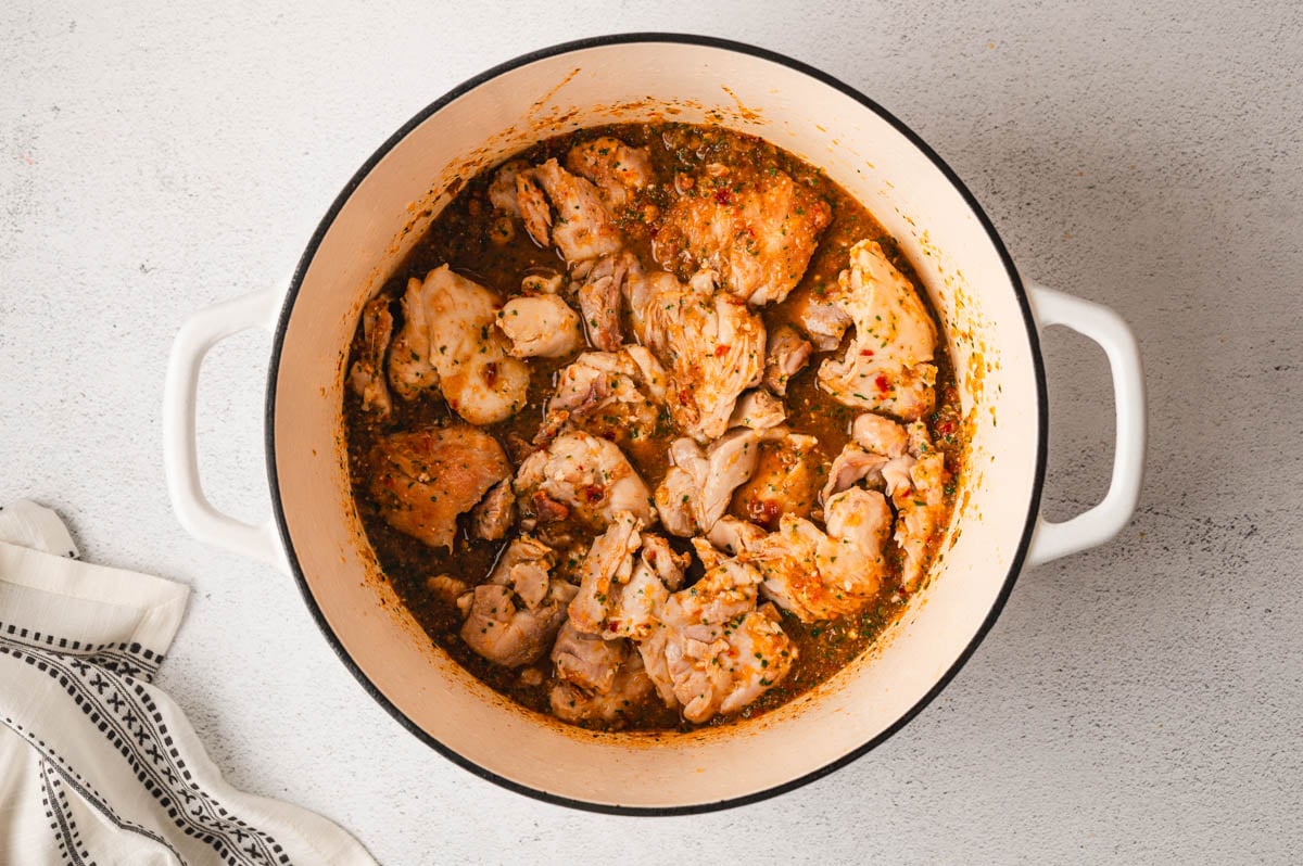 Chicken thighs simmering in a large pot.