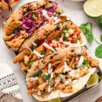 Chipotle Chicken in charred tortillas with cabbage, sour cream and cheese.