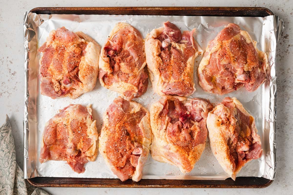 Uncooked chicken thighs on a sheet pan