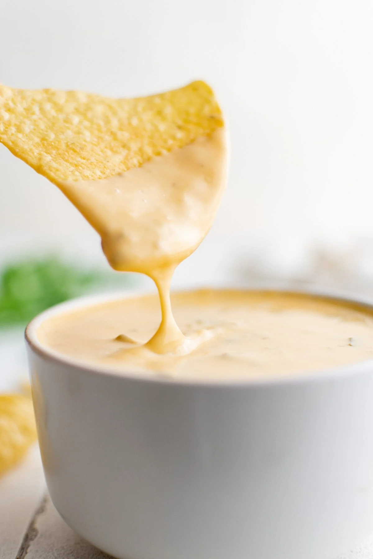 chip dipped in nacho cheese in a white bowl