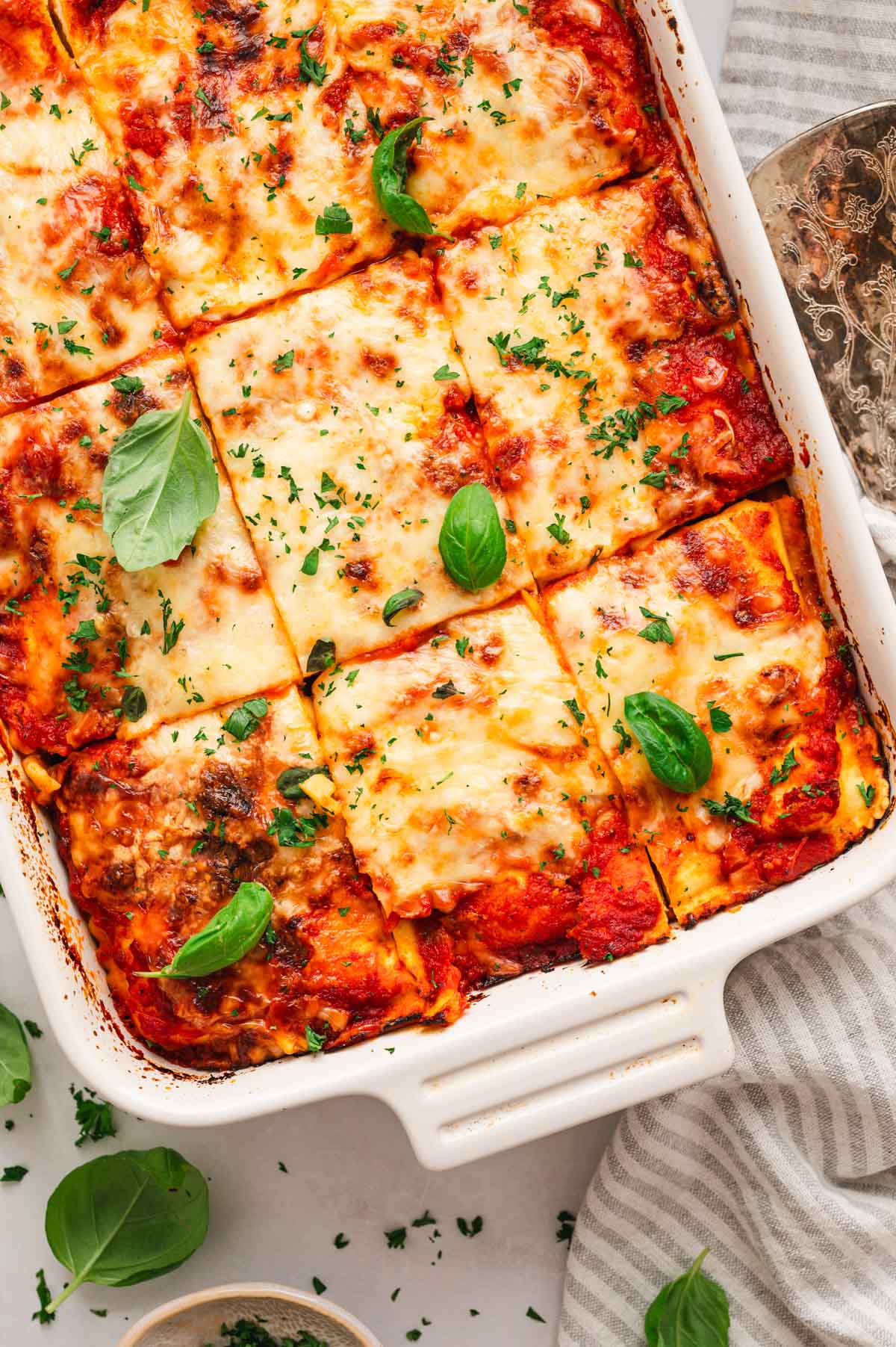 Lasagna in a white dish sliced into squares.