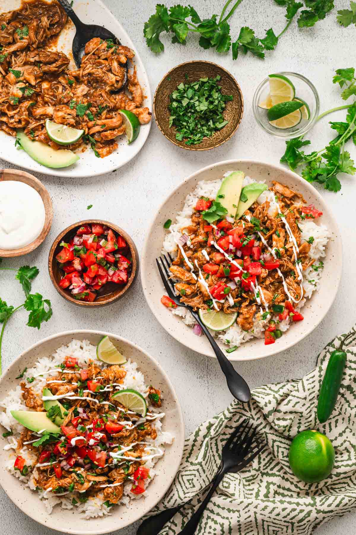 2 white plates with rice, shredded chicken, pico di gallo.