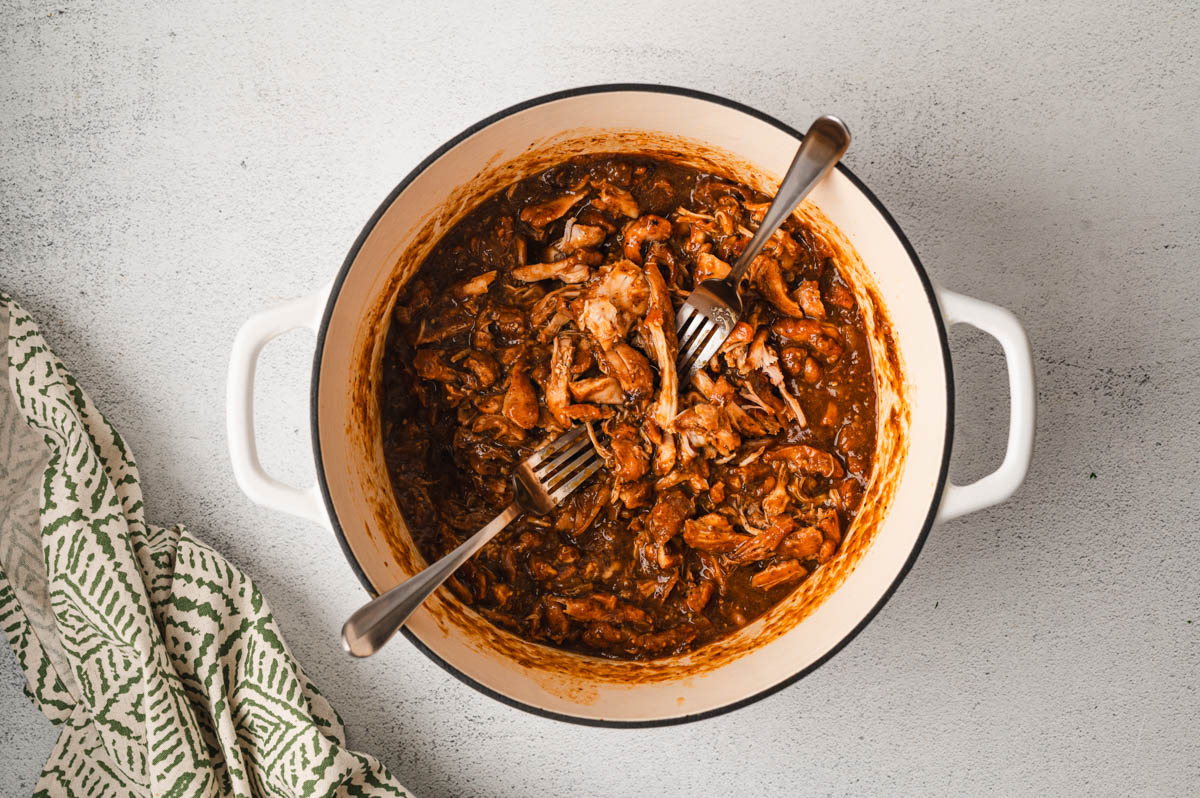 Shredded chicken with sauce in a large pot.