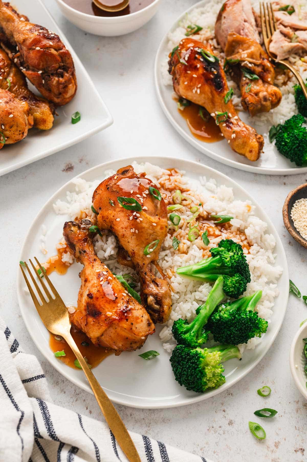 A white dinner plate with chicken drumsticks, rice an dbroccoli.