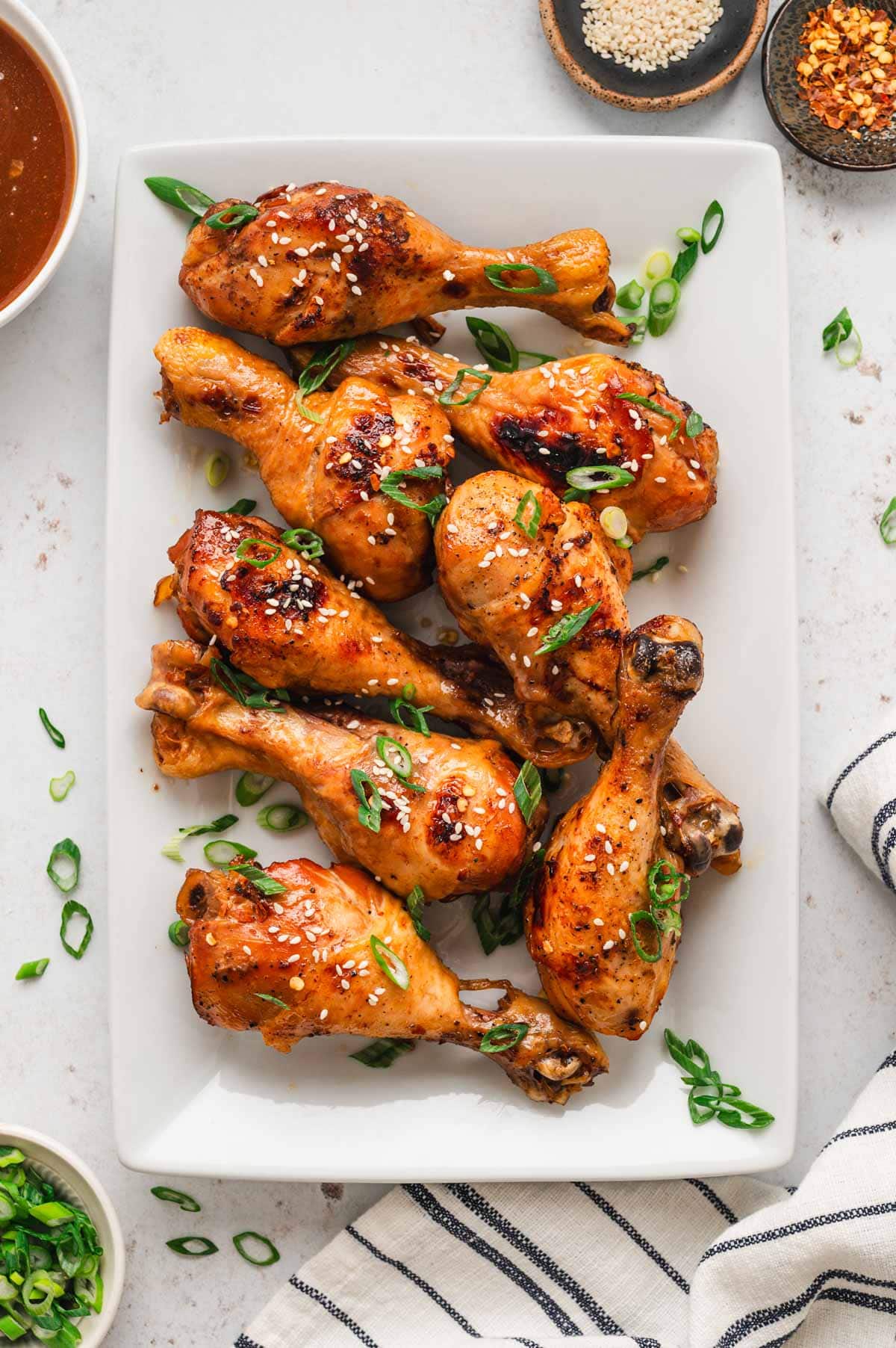 A pile of chicken drumsticks on a white platter. 