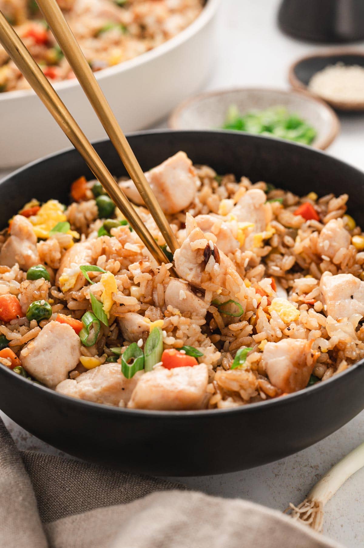 chicken fried rice in a black bowl with chopsticks.