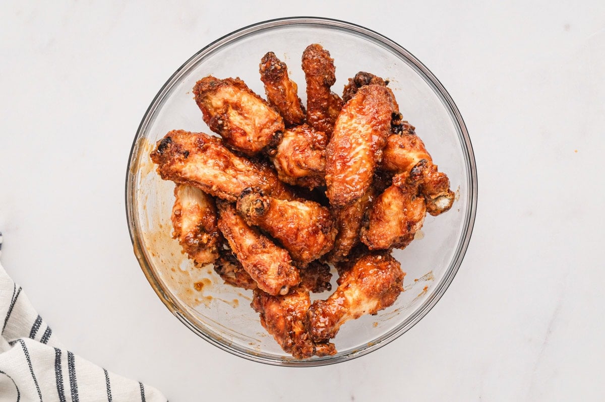 baked chicken wings in a glass bowl with marinade sauce.