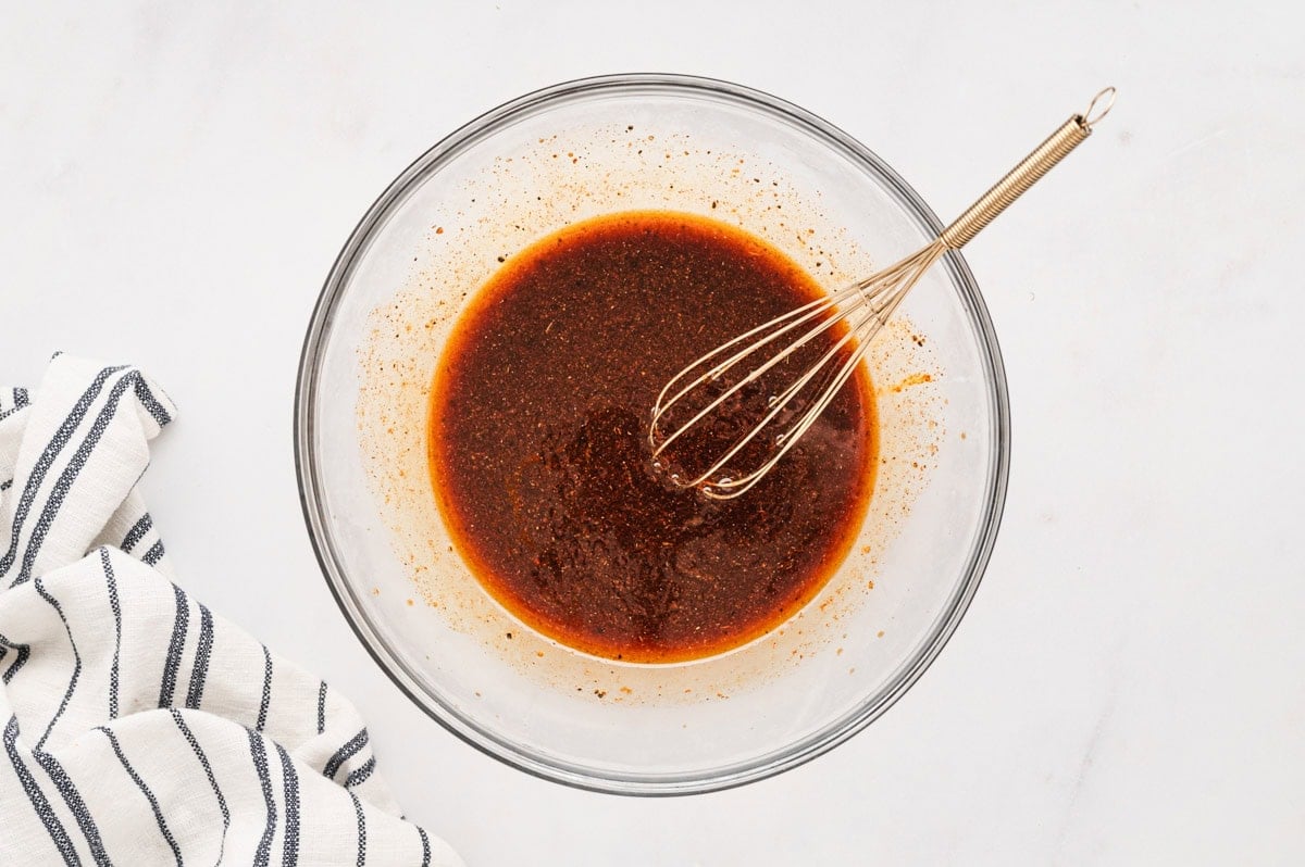 Marinade in a glass bowl with a whisk.